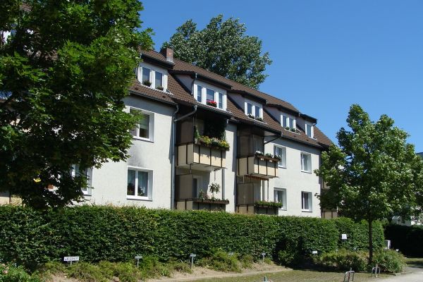 Mehrfamilienhaus mit Hecke und Bäumen